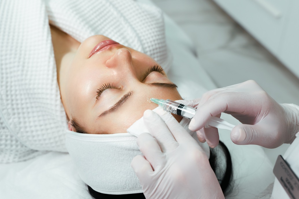 The doctor cosmetologist makes the rejuvenating facial injections procedure for tightening and smoothing wrinkles on the face skin of a beautiful, young woman in a beauty salon. Cosmetology,